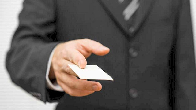 Man in suit handing over white business card